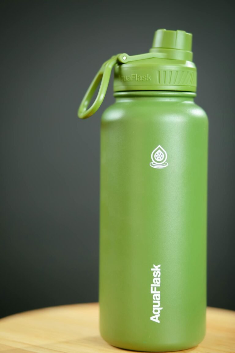 Green AquaFlask vacuum insulated bottle with secure lid, perfect for outdoor hydration.