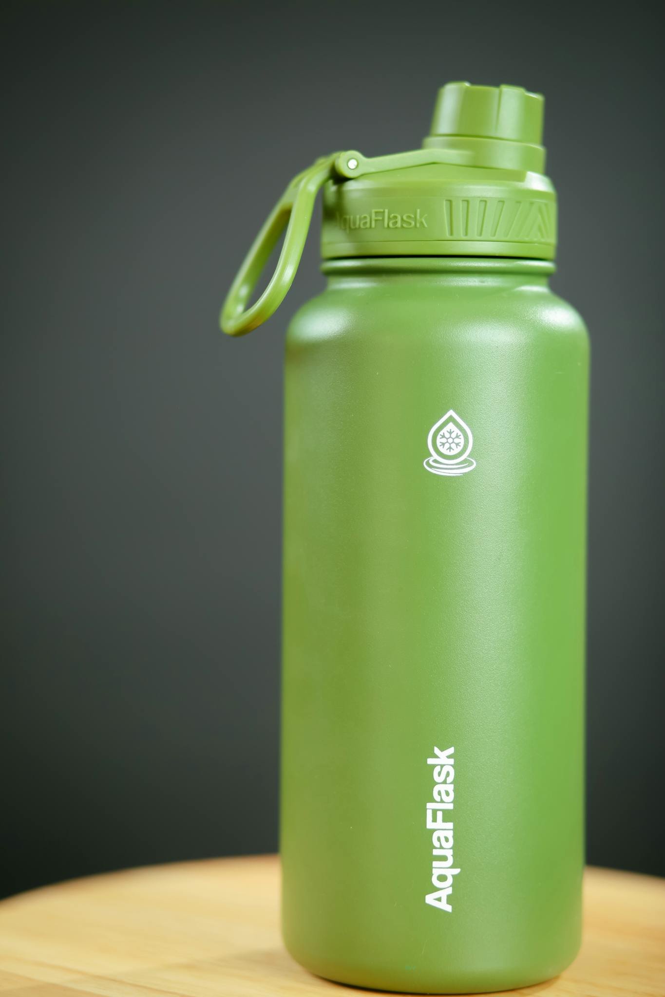 Green AquaFlask vacuum insulated bottle with secure lid, perfect for outdoor hydration.